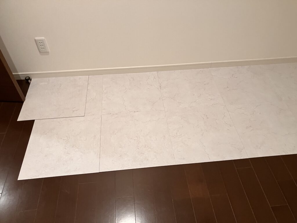 引っ越し前のみなとみらいの床に白いタイルをひく様子