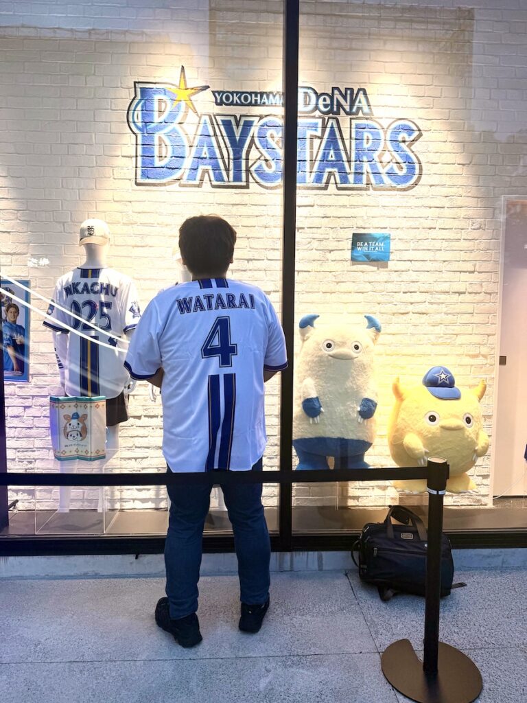 横浜DeNAベイスターズ渡会隆輝選手の背番号4のユニフォームを着て球団グッズのショーウインドー前に立つ後ろ姿